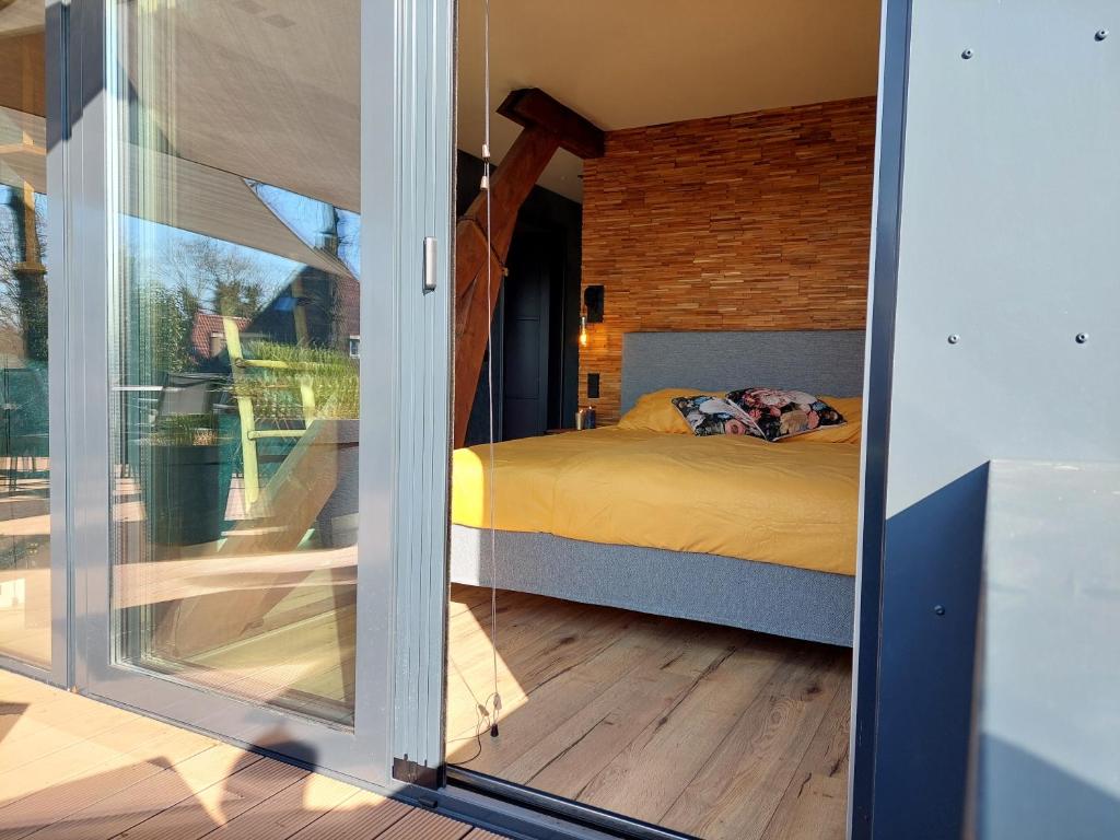 1 dormitorio con 1 cama a través de una puerta corredera de cristal en B&B Vierlingsbeek, Appartement Onder één dak en tuin-chalet en Vierlingsbeek