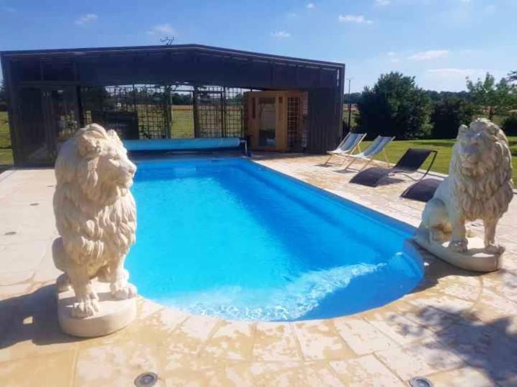 two statues of dogs standing next to a swimming pool at Villa de 5 chambres avec piscine privee jacuzzi et jardin clos a Saint Clair d'Arcey in Bernay
