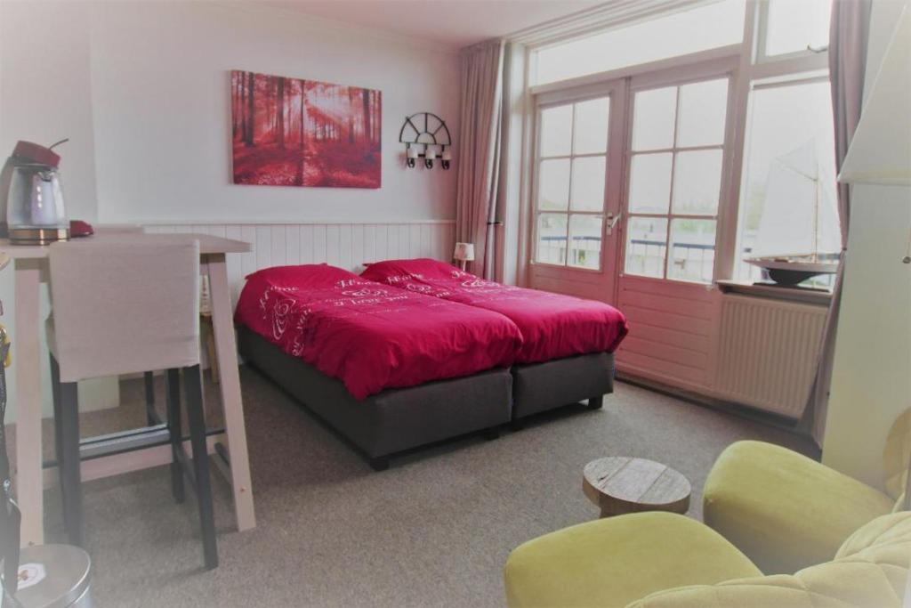 a bedroom with a red bed and a table and chairs at Texelzon in Den Hoorn