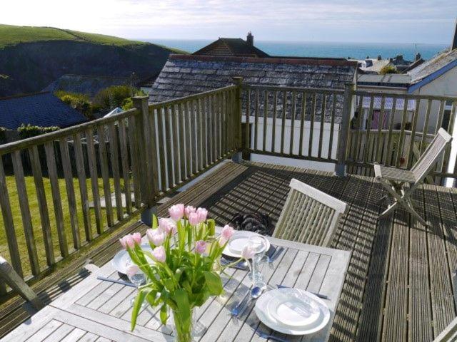 a table with a vase of flowers on a deck at Bay View, Port Isaac in Port Isaac