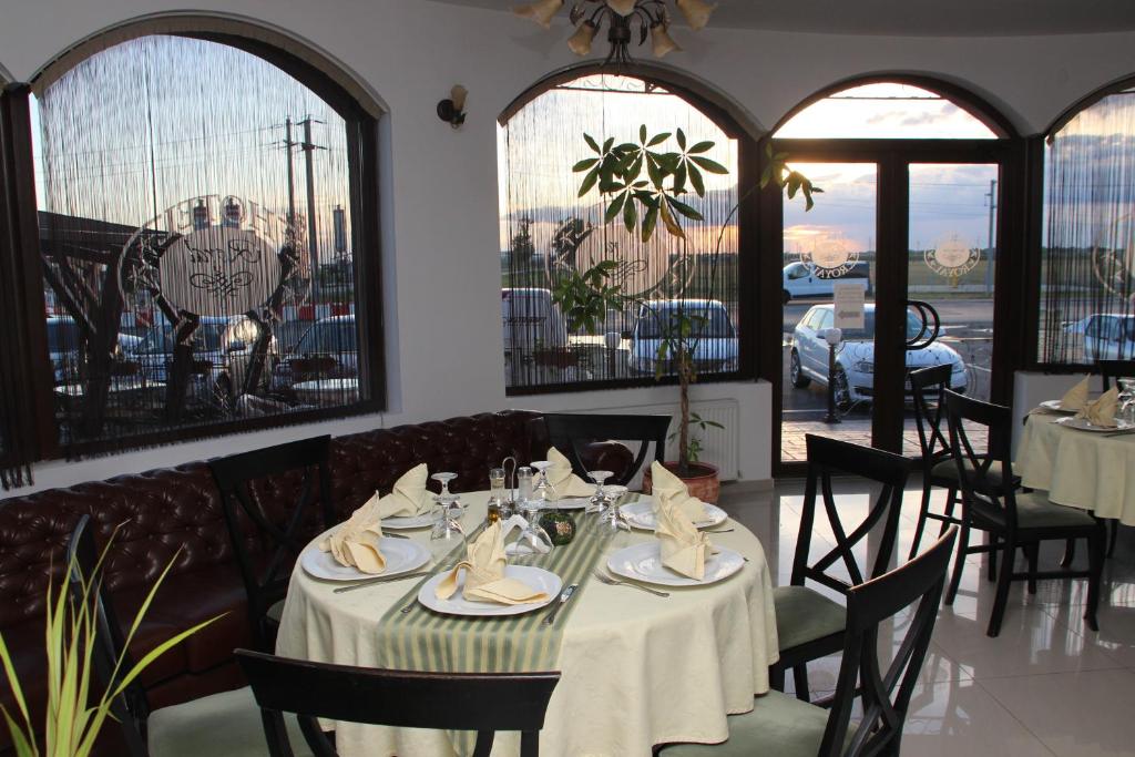 a dining room with tables and chairs and windows at Hotel Royal 2 in Urziceni