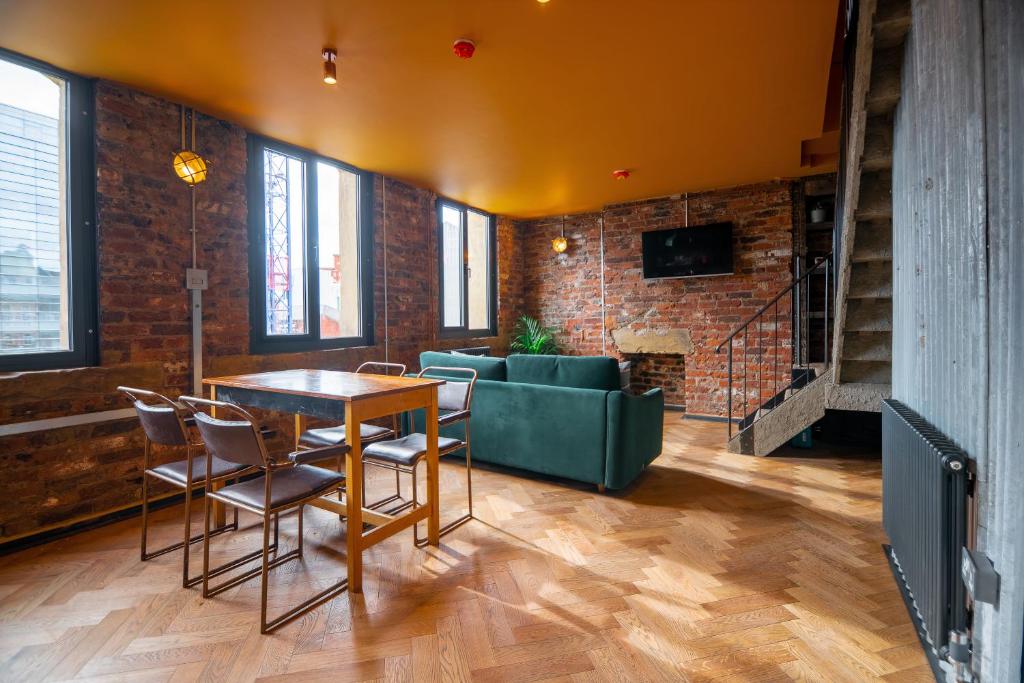 uma sala de estar com uma mesa e cadeiras e um sofá em Rooms by Green Room em Leeds