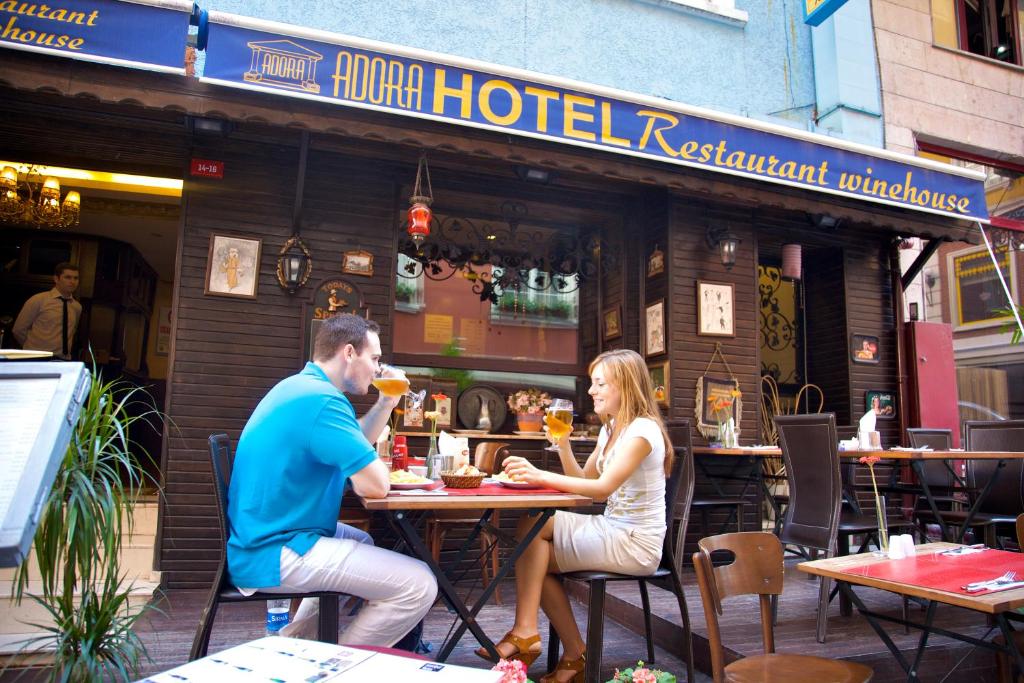 un hombre y una mujer sentados en una mesa fuera de un restaurante de hotel en Adora Hotel Cafe & Restaurant en Estambul