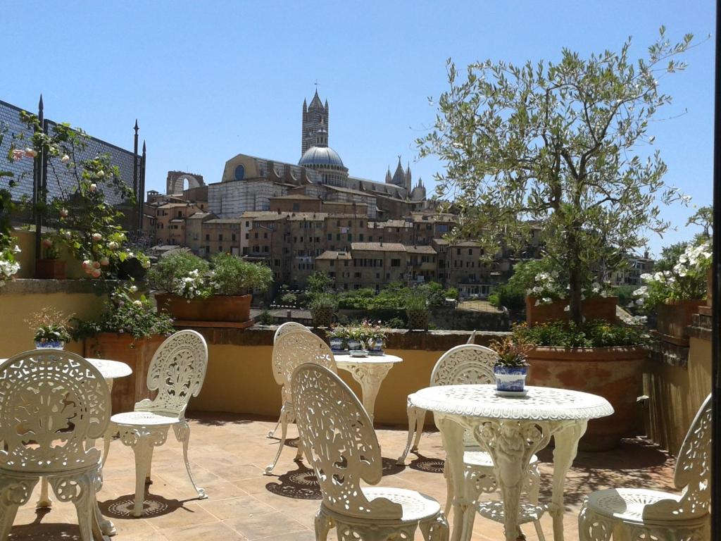 un patio con mesas y sillas y vistas a la ciudad en Residenza d'Epoca Campo Regio Relais, en Siena