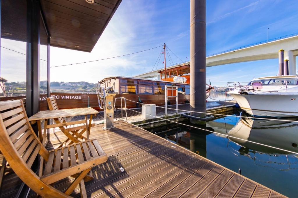 um deque de madeira com um banco e um barco na água em Oporto Douro Floating House em Porto