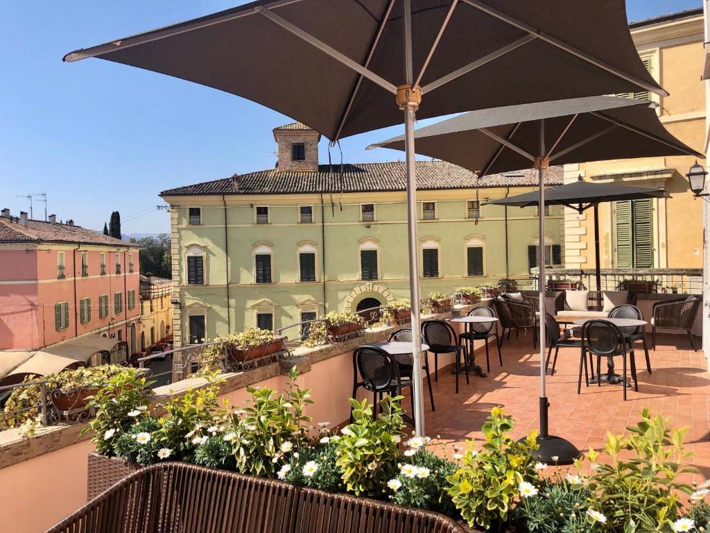 einen Balkon mit Tischen, Stühlen und einem Sonnenschirm in der Unterkunft Casa Maghinardo in Brisighella