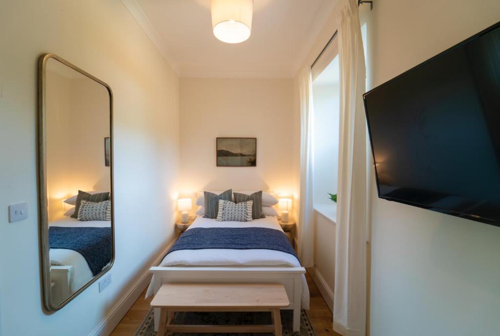 a small bedroom with a bed and a large mirror at Foundry Farm Apartment in Hexham