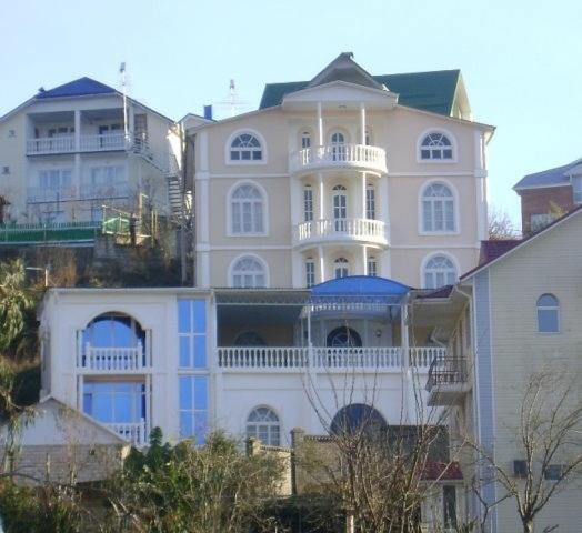 a large white house on top of a hill at Nikos Guest House in Adler