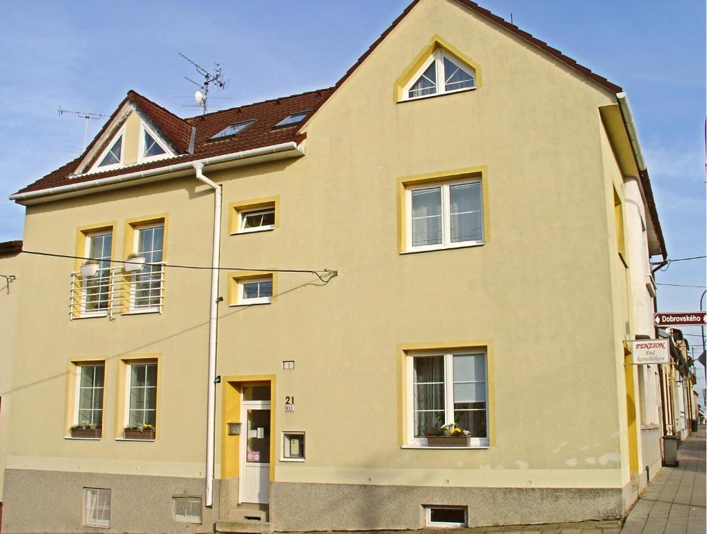 a yellow house with a brown roof at Penzion pod Kostelíčkem in Třebíč