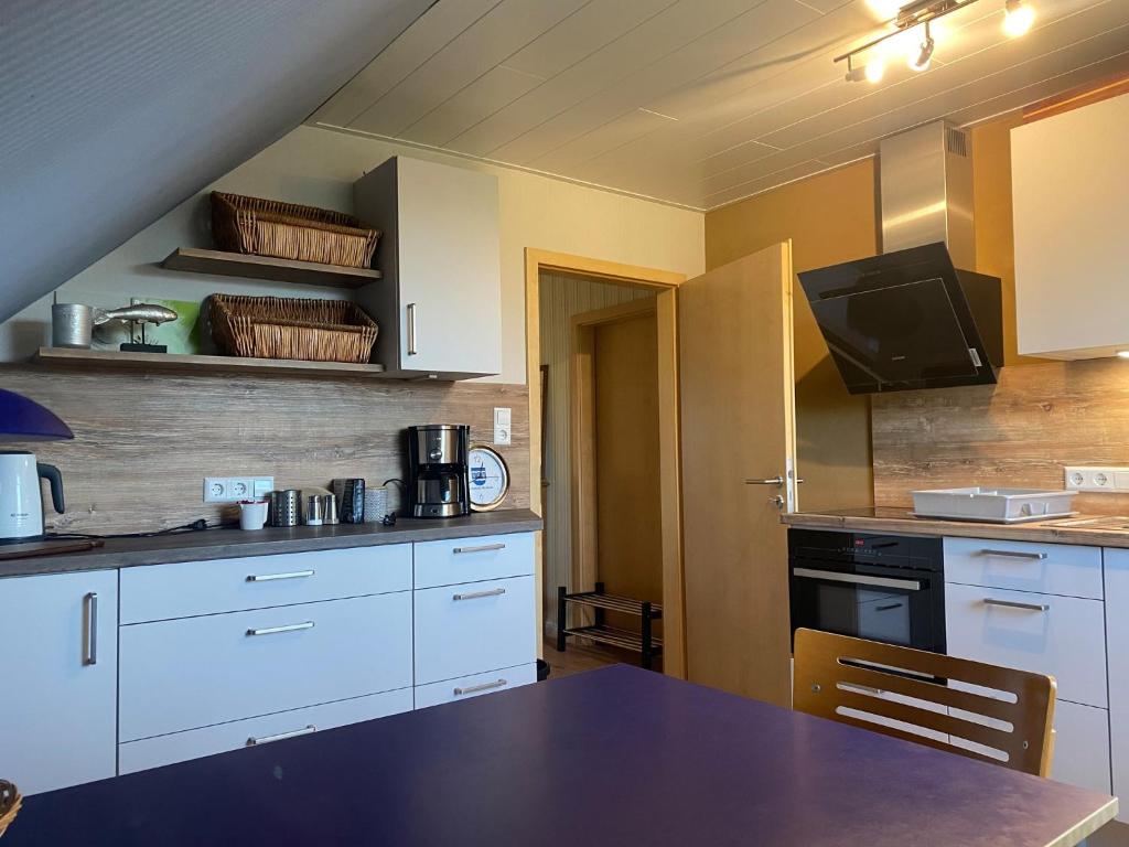 una cocina con armarios blancos y una mesa. en Ferienwohnung Brügge - zwischen Eider & Nord-Ostsee-Kanal, en Breiholz