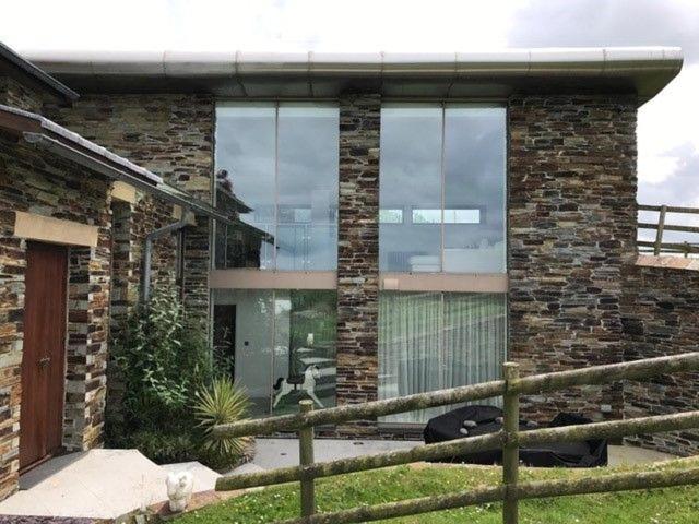 a building with large glass windows on the side of it at Fursewood, Widemouth Bay, Cornwall in Poundstock