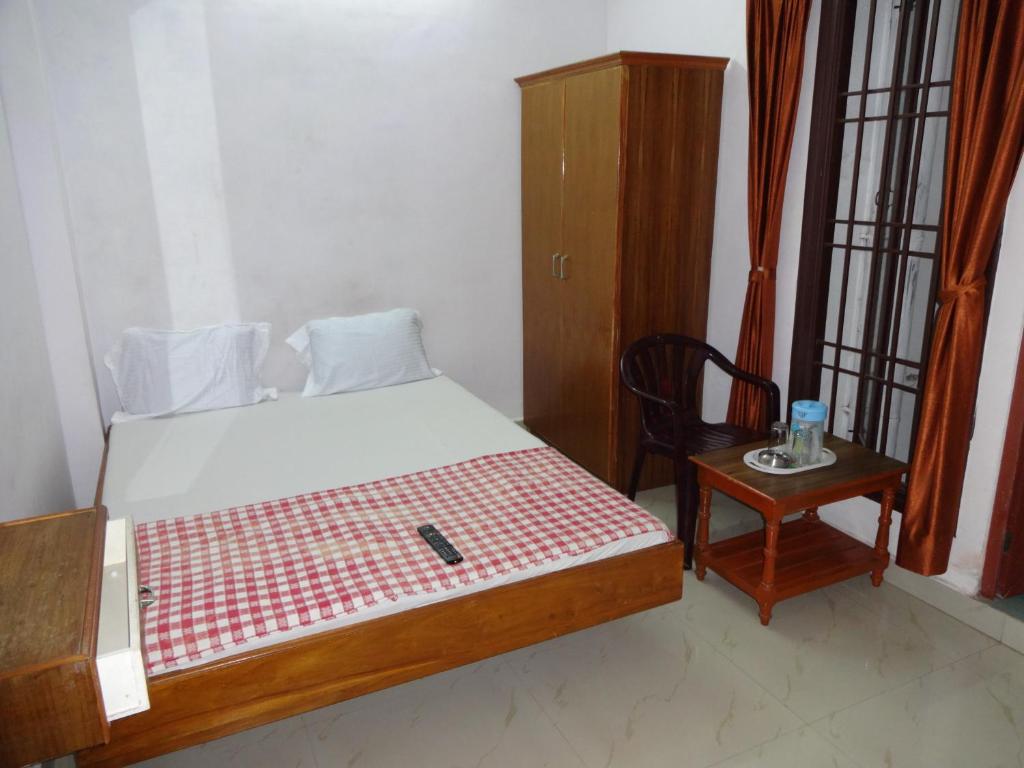 een slaapkamer met een bed, een stoel en een tafel bij R M Guest House in Kālapettai