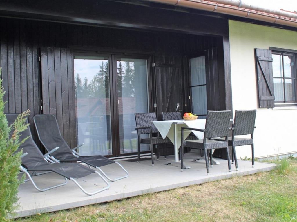 um pátio com uma mesa e cadeiras em Ferienhaus Nr 14, Kategorie Komfort, Feriendorf Hochbergle, Allgäu em Bichel