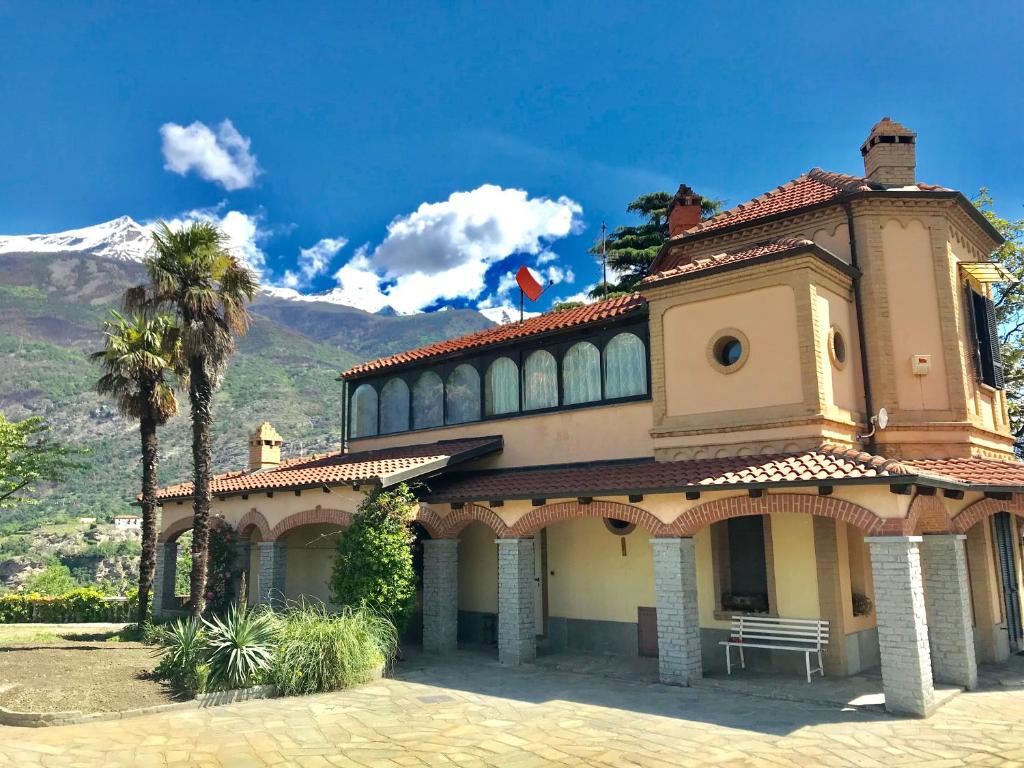 ein Gebäude mit einer Palme und Bergen im Hintergrund in der Unterkunft Villa Belvedere in Susa