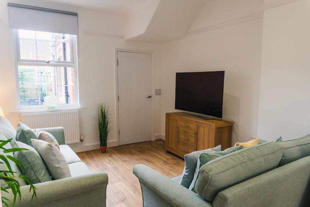 a living room with two couches and a flat screen tv at Villiers House - Comfy Stylish Home in Leamington Spa