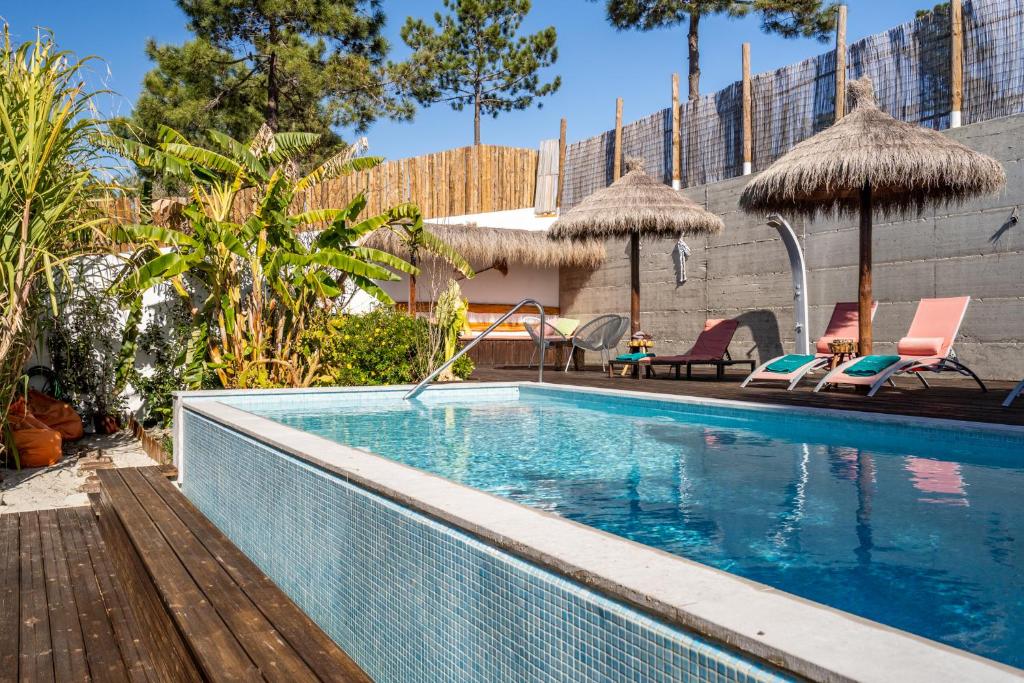 a swimming pool with chairs and umbrellas next to a building at Akivillas Setúbal Paradise in Setúbal