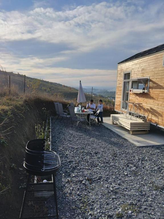 dos personas sentadas en una mesa fuera de un edificio en Tiny House Cluj with Jacuzzi, en Sînnicoară