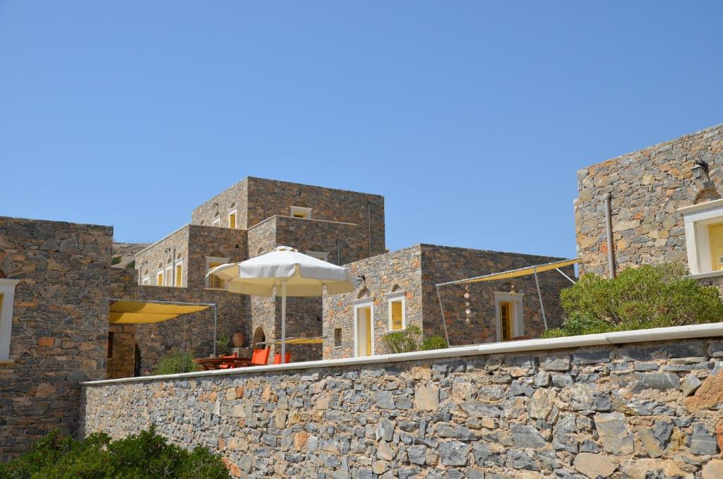 a stone wall with an umbrella on top of it at Archipelagos Boutique Hotel in Schinoussa