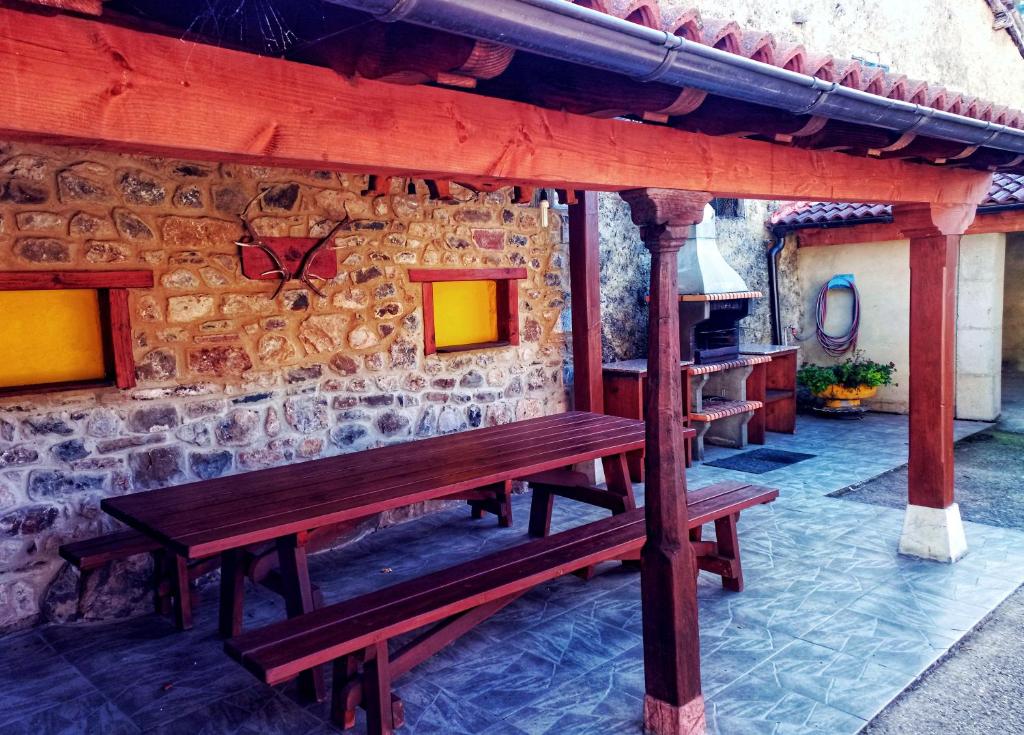 un banco de madera sentado frente a una pared de piedra en Casa Rural Burón, en Posada de Valdeón