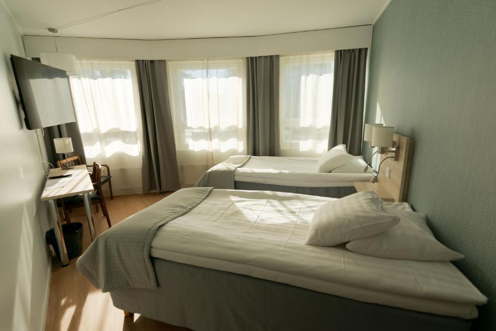 a hotel room with two beds and two windows at Hotel Hirvi in Äänekoski