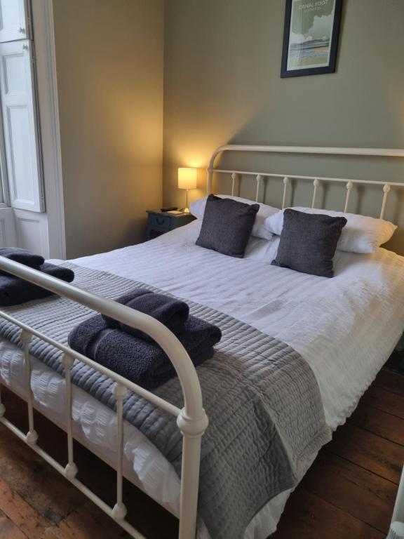 a bedroom with a white bed with black pillows at The Butler's House in Ulverston