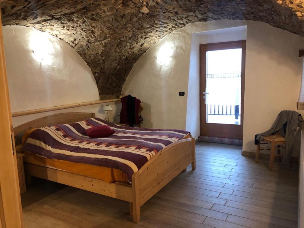 - une chambre avec un lit dans une pièce dotée d'un mur en pierre dans l'établissement CASA DIAF appartamento incantevole Carano Ville di Fiemme, à Carano
