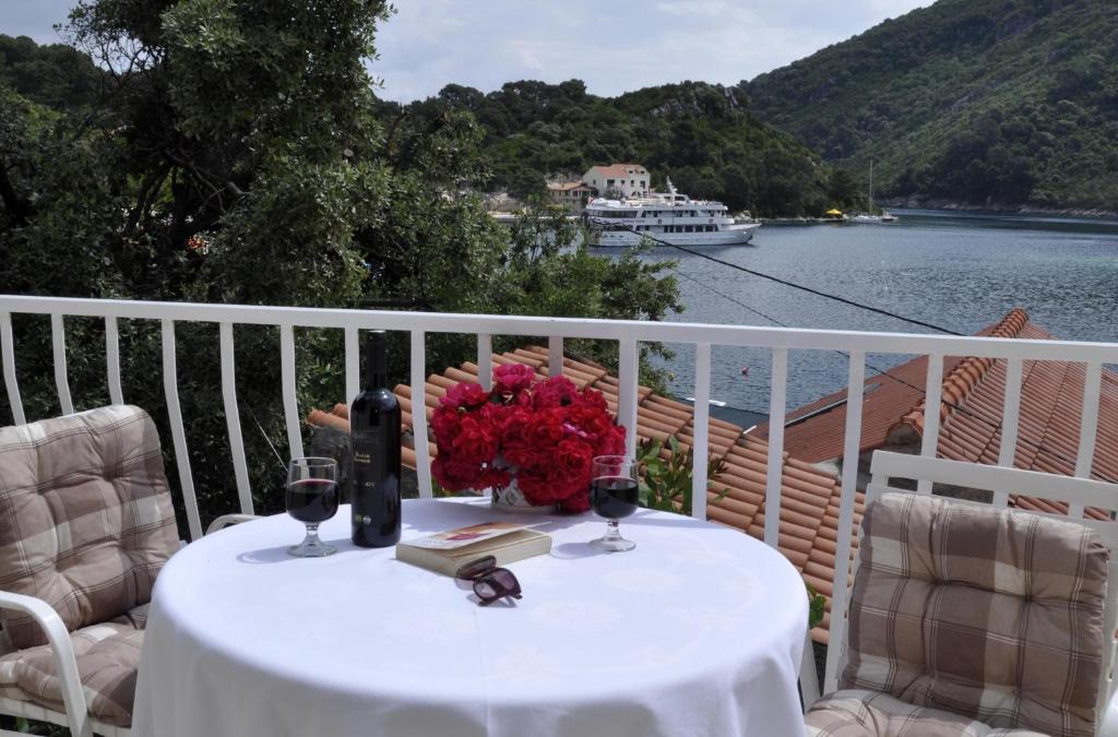 a table with wine glasses and a vase of flowers on a balcony at Apartment Danijela in Okuklje