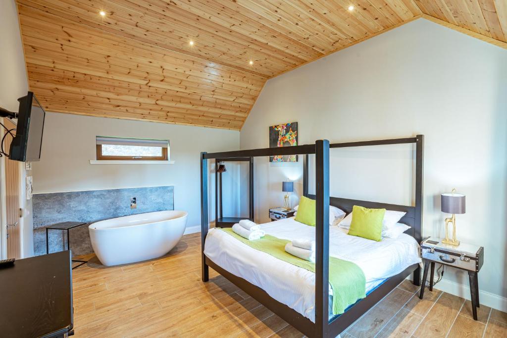 1 dormitorio con bañera, 1 cama y baño en Kestrel Lodge 7 with Hot Tub en Newton Stewart