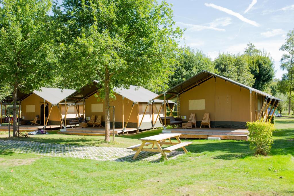 a group of tents in a park with a picnic table at Safaritent Val d'Or in Enscherange