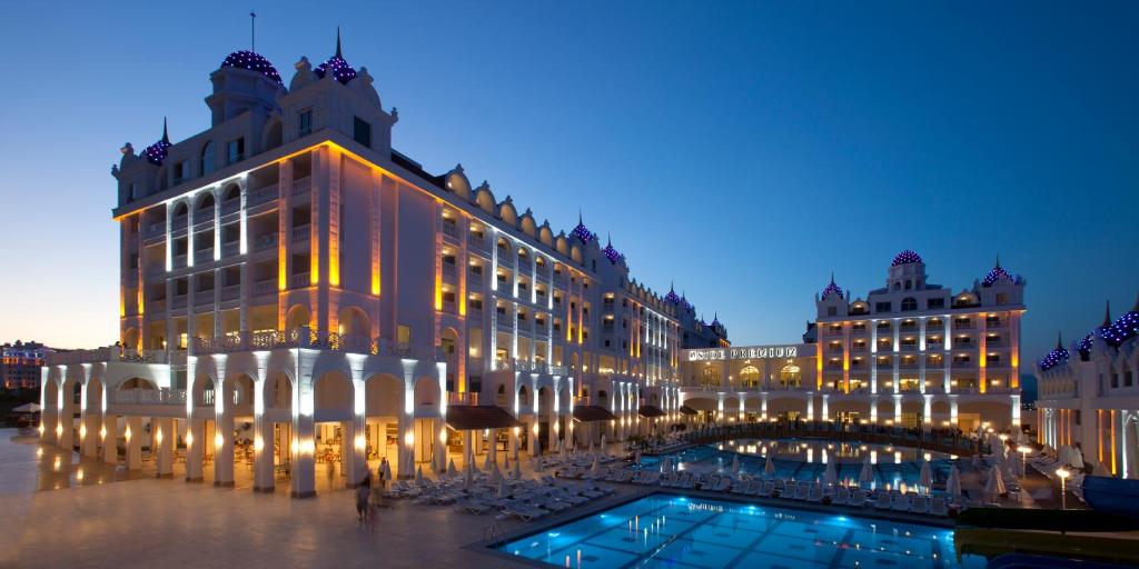 a building with a pool in front of it at night at Oz Hotels Side Premium in Side