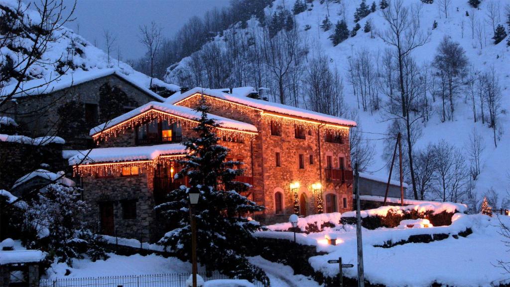 una casa cubierta de luces de Navidad en la nieve en Mas Can Buixat en Setcases