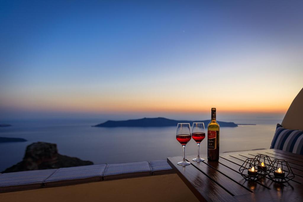 stolik z dwoma kieliszkami wina i butelką w obiekcie Azure Villa Santorini w Imerovíglion