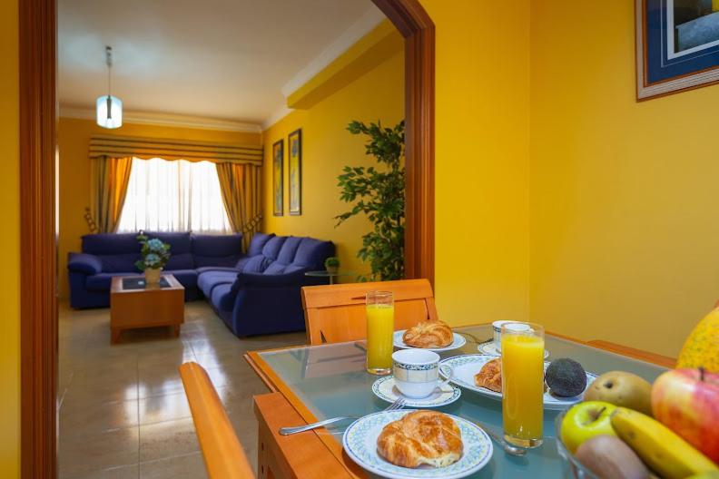 a dining room table with plates of food and orange juice at DUPLEX EN EL CENTRO DE GALDAR in Gáldar