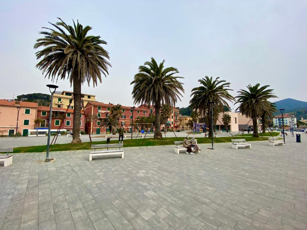 a person sitting on a bench in a park with palm trees at Appartamento LA ROSA in Riva Trigoso