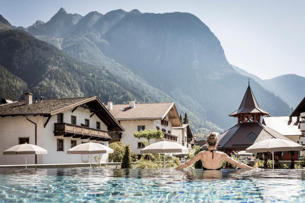 a woman swimming in a pool in the mountains at Posthotel Kassl 4-Sterne-Superior in Oetz