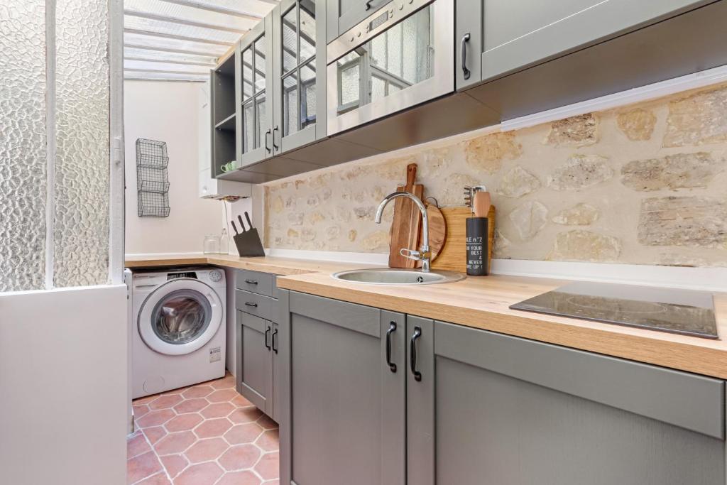 eine Küche mit einer Spüle und einer Waschmaschine in der Unterkunft Splendid Parisian Flat 5P - Montorgueil in Paris