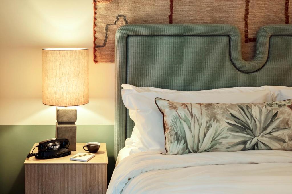a bed with a lamp and a clock on a night stand at The Hoxton, Poblenou in Barcelona