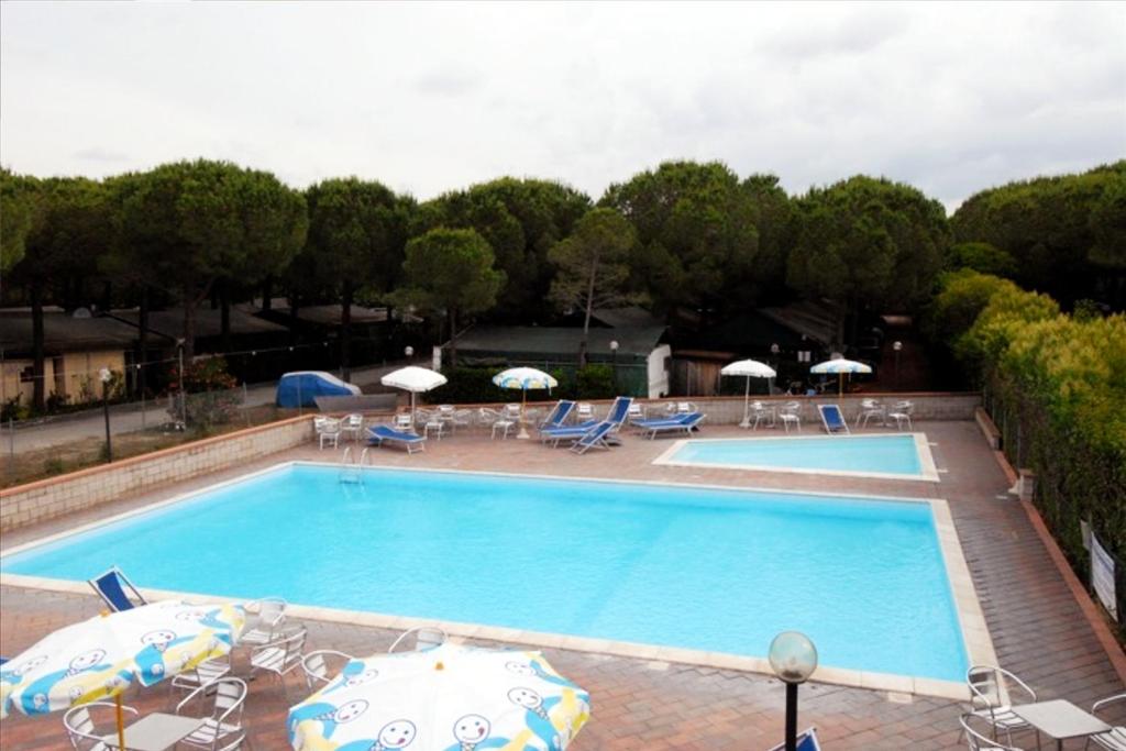 una gran piscina con sombrillas y sillas en Parco Vacanze La Rosa dei Venti, en Marina di Bibbona