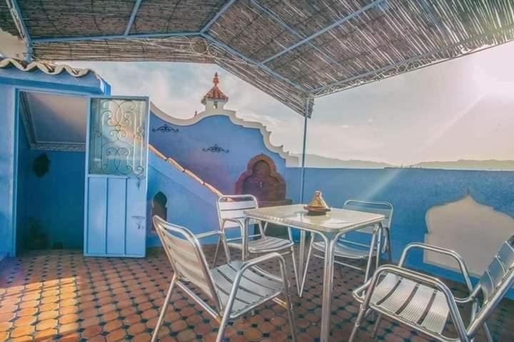 un tavolo con sedie in una stanza con un murale di Dar Lalla chafia 2 a Chefchaouen