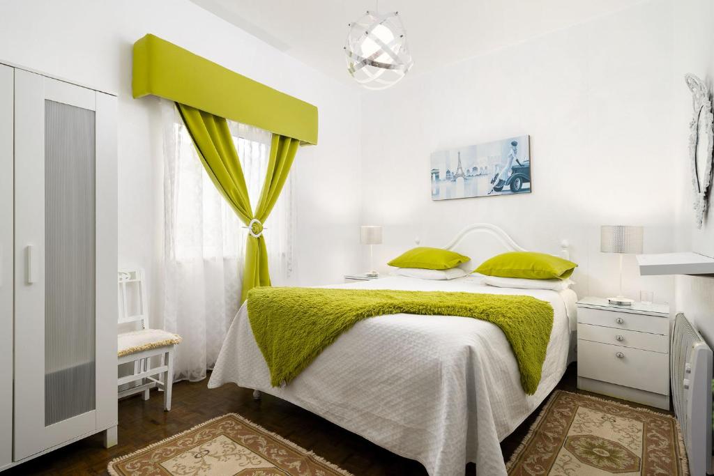 - une chambre avec un lit doté de draps verts et une fenêtre dans l'établissement Casa Morais, à Odeceixe
