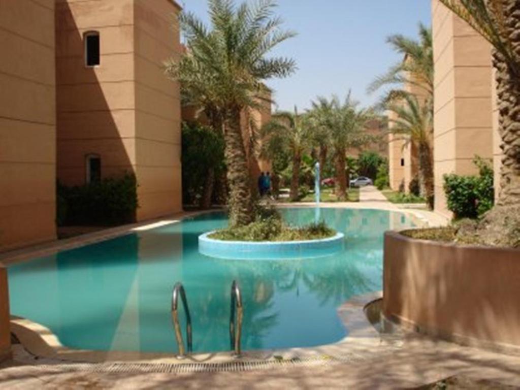 a swimming pool in a resort with palm trees at Riad Lalla Zahra in Marrakesh