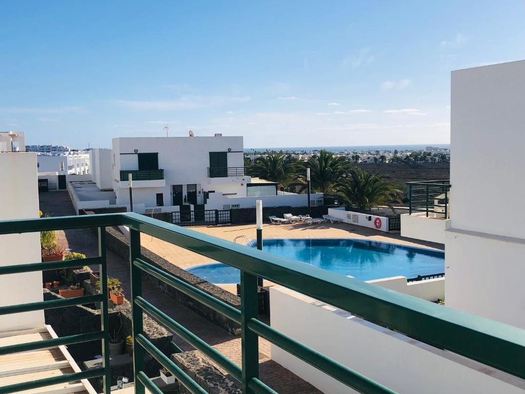 ein Balkon mit einem Swimmingpool auf einem Gebäude in der Unterkunft Alegranza, apartamento de 3 habitaciones en Lanzarote in Costa Teguise