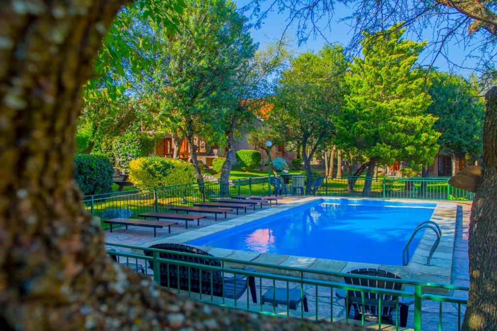 a swimming pool with benches and trees in a park at Complejo Vip Houses in Merlo