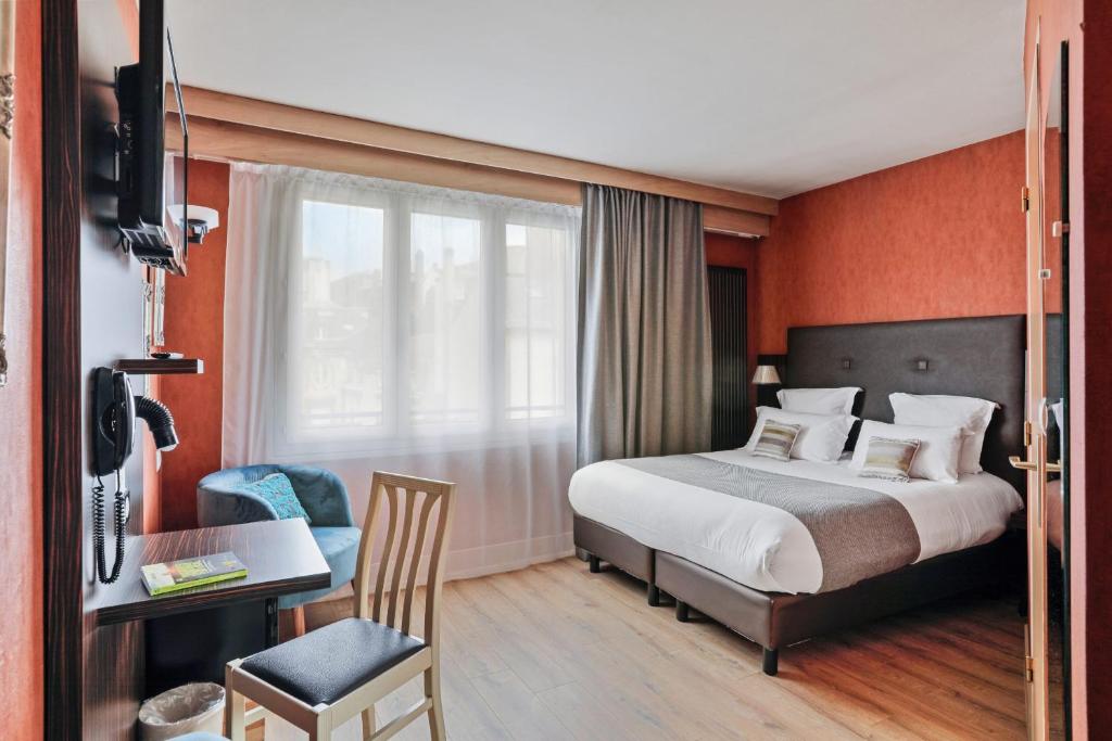 a hotel room with a bed and a desk and a window at Urban Style hotel de l'Europe in Rouen
