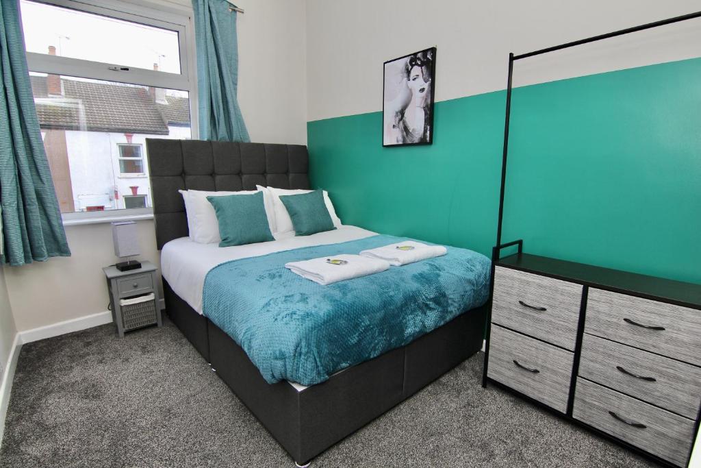 a bedroom with a bed and a blue wall at Mount Haven's Rest - Free Parking, Netflix & Private Back Garden in Coventry
