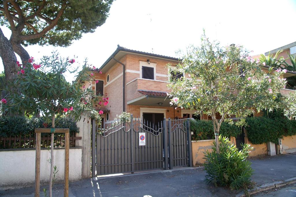 a house with a gate and trees in front of it at Ville sul Mare in Marina di Grosseto