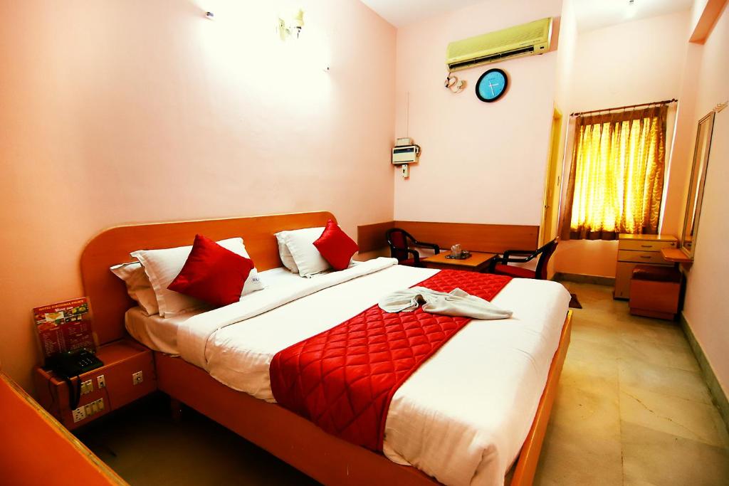 a bedroom with a large bed with red pillows at Hotel Kirthikaa Palace Salem in Salem