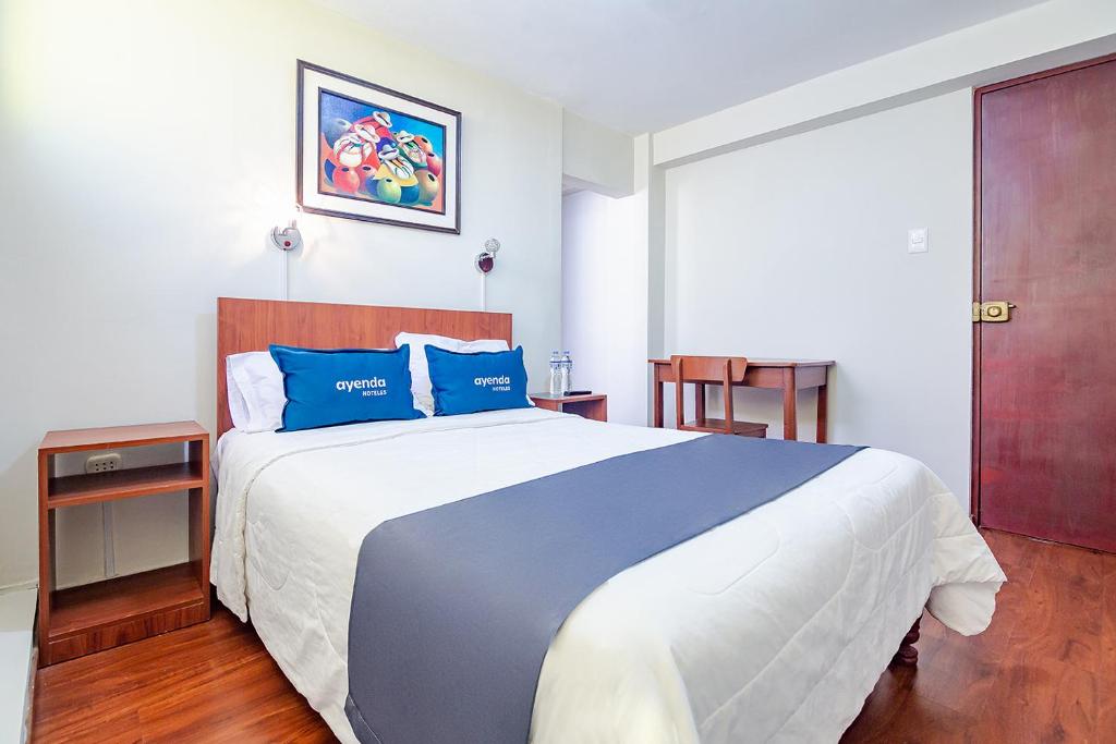 1 dormitorio con 1 cama grande con almohadas azules en Ayenda Internacional de Arequipa, en Arequipa