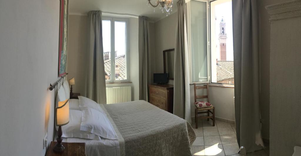 a bedroom with a bed and two windows at I Terzi Di Siena - Rooms Only in Siena