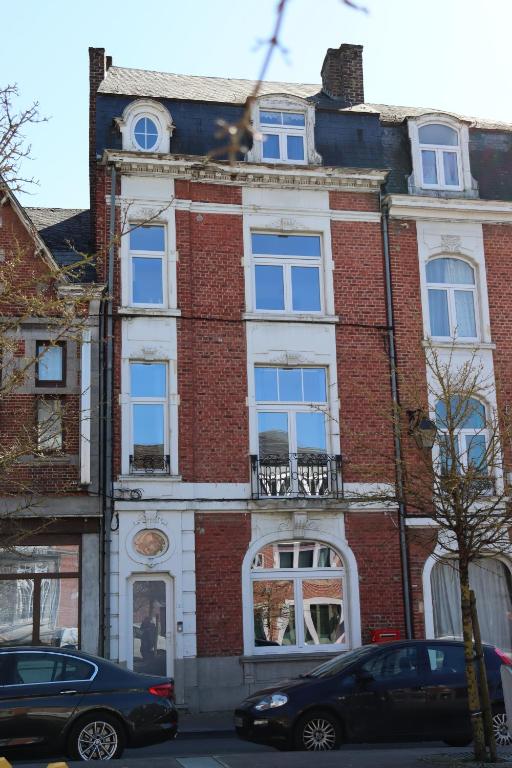 a red brick building with white windows on a street at Le Patenier in Dinant